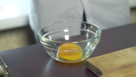 Egg-yolk-falling-in-glass-bowl.-Food-ingredient-preparing-ingredients-for-baking
