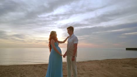 Pregnant-couple-on-beach-at-sunrise.-Man-and-woman-on-sea-beach