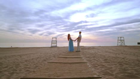 Couple-holding-hands-on-sea-beach.-Love-couple-beach-sunrise.-Pregnant-couple