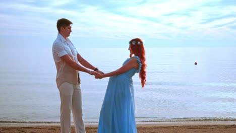 Young-people-holding-hands-on-sea-beach.-Pregnant-couple-beach