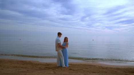 Pregnant-couple-beach.-Pregnant-couple-hugging-on-sea-beach.-Love-couple-beach