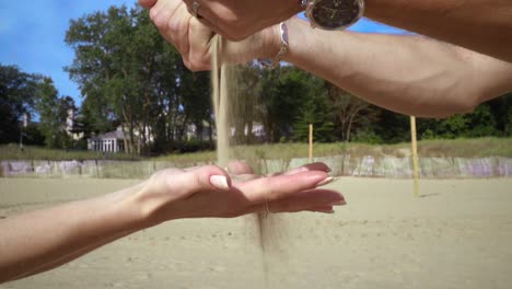 Sand-pouring-from-male-hand-to-woman-hand.-Hands-sand.-Hand-pour-sand