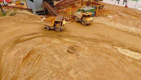 Dumper-trucks-with-sand-standing-on-territory-industrial-factory.-Aerial-view