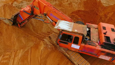Orange-crawler-excavator-standing-on-sand-mine.-Mining-excavator