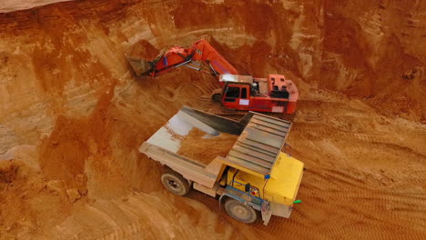 Excavator-pouring-sand-in-mining-truck-at-quarry.-Excavator-loading-dump-truck