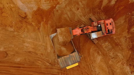 Top-view-of-excavator-pouring-sand-in-dump-truck.-Mining-industry