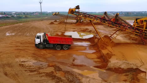Drone-view-of-mining-conveyor-pour-sand-in-dumper-truck.-Mining-machinery
