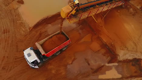 Mining-conveyor-loading-sand-in-dumper-truck.-Aerial-view-of-sand-mining-process