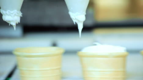 Automated-production-line.-Closeup-of-ice-cream-pouring-in-waffle-cup-at-factory