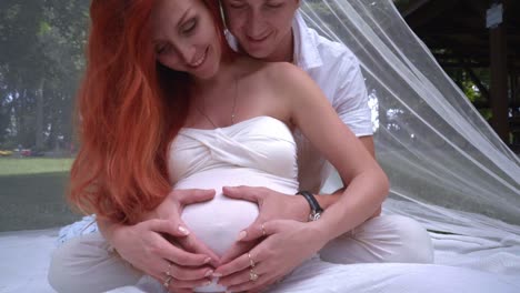 Happy-couple-hugging-pregnant-belly.-Couple-hands-in-heart-on-pregnant-belly