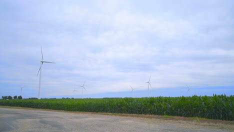 Wind-turbines-farm.-Wind-generators-landscape.-Rustic-road-under-clouds-sky
