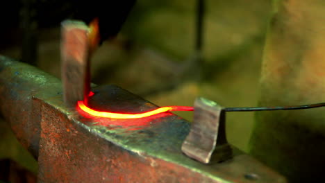 Smith-forming-red-hot-iron-in-hook-on-anvil.-Hot-metal-on-anvil-in-workshop