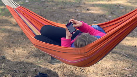 Girl-in-hammock-using-smartphone.-Young-woman-surfing-internet-on-mobile-phone