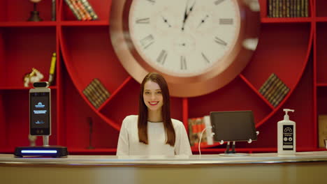 Receptionist-looking-camera-in-hotel-interior.-Woman-smiling-in-modern-space.