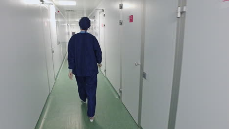 Back-view-of-female-doctor-in-protective-uniform-walking-in-hospital-corridor