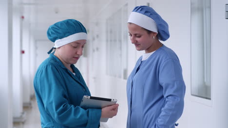 Two-women-using-tablet-in-white-hallway.-Lab-women-looking-tablet-and-smiling