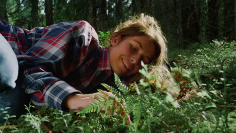 Tourist-relaxing-on-grass-in-summer-forest.-Young-woman-lying-on-ground-in-woods