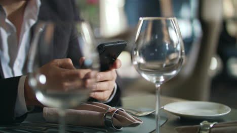 Male-hands-typing-phone-at-restaurant-table.-Businessman-using-smartphone