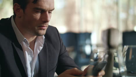 Businessman-looking-mobile-phone-at-restaurant.-Handsome-man-using-cellphone