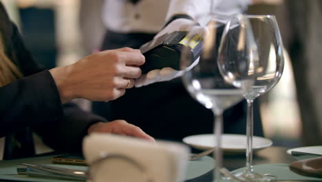 Female-hand-paying-by-bank-card-in-restaurant.-Contactless-payment