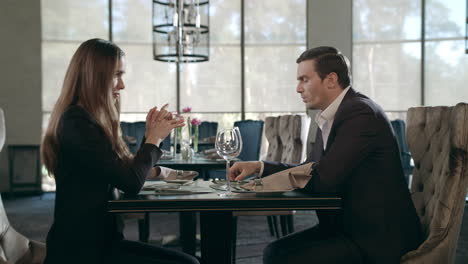 Young-couple-meeting-at-restaurant.-Business-man-and-woman-talking-at-cafe-table
