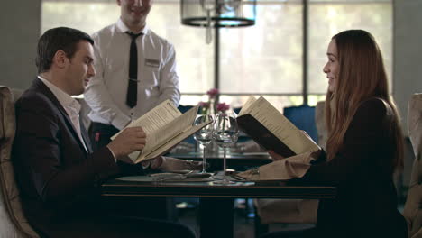 Happy-couple-reading-menu-in-restaurant.-Business-people-choosing-food-in-cafe