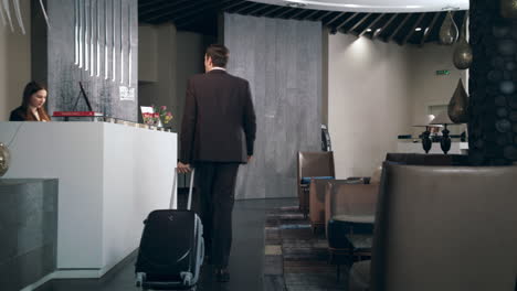 Businessman-with-travel-suitcase-arriving-in-hotel-at-holiday