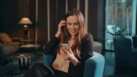 Happy-woman-using-smartphone-for-video-call-online-at-hotel-lounge