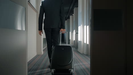 Businessman-with-travel-suitcase-walking-at-hotel-corridor.-Man-arriving-hotel