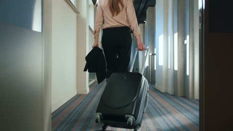 Businesswoman-with-travel-suitcase-walking-at-hotel-corridor
