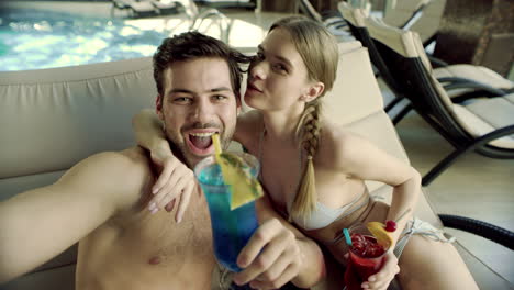 Macro-of-beautiful-couple-making-selfie-near-pool-with-cocktails.