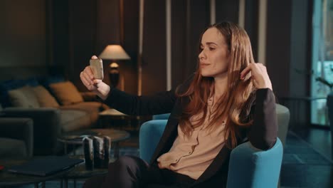 Business-woman-doing-mobile-selfie-by-smartphone-in-chair-lounge-room