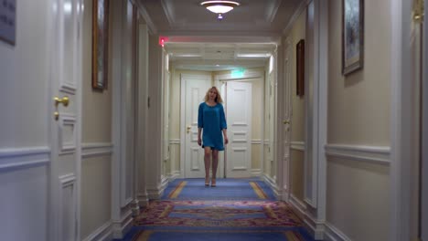 Beautiful-woman-in-blue-dress-walking-along-corridor-at-luxury-mansion
