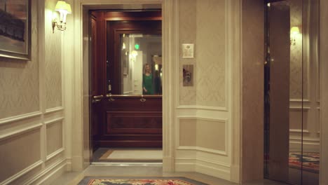 Opening-empty-elevator-in-hallway-luxury-hotel.-Woman-entering-in-lift-car