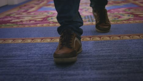Male-feet-in-sport-shoes-walking-on-carpet-floor-in-corridor-guest-hotel