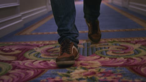 Man-legs-in-brown-sneakers-walking-on-blue-carpet-on-long-corrido