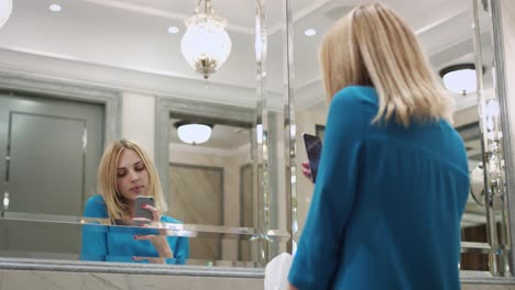 Beautiful-woman-making-selfie-photo-on-mobile-phone-front-mirror-in-bathroom