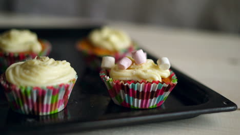 Marshmallow-candies-falls-to-muffin.-Decorating-cupcake