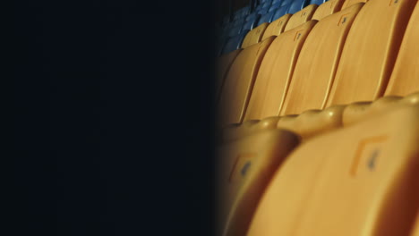 Empty-yellow-and-blue-seats-in-football-stadium.-Close-up-row-of-plastic-chairs