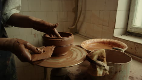 Master-working-with-wet-clay-pot-in-pottery.-Woman-hands-making-line-on-product