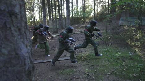 Paintball-player-running-on-battle-field-during-shooting-game-in-summer-forest