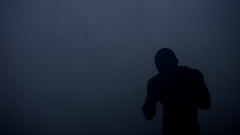 Boxer-silhouette-at-dark-studio.-Mma-fighter-warming-up-before-fight
