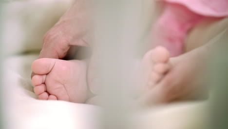 Mother-hand-touching-infant-baby-foot.-Family-tenderness.-Maternity-care