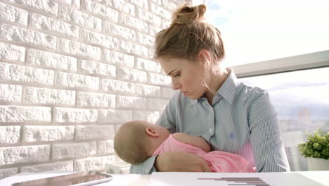Business-woman-care-baby-at-light-window.-Working-mom-with-child-at-office