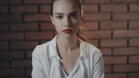 Arrogant-woman-with-red-lips-confidently-looking-to-camera-on-brick-copyspace