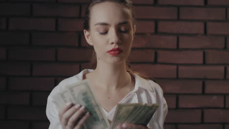 Serious-woman-counting-money-banknotes-on-brick-wall.-Wealthy-businesswoman