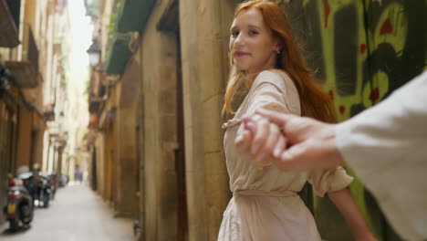 Closeup-woman-holding-man-hand-in-old-city-street.-Pov-of-romantic-couple-hands