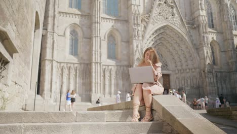 Laughing-woman-working-with-laptop-near-cathedral.-Smiling-girl-getting-message