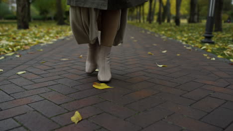 Female-feet-in-stylish-boots-going-in-october-park.-Woman-legs-walking-path.