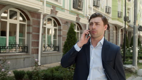 Closeup-businessman-walking-at-beautiful-street.-Man-talking-phone-outside
